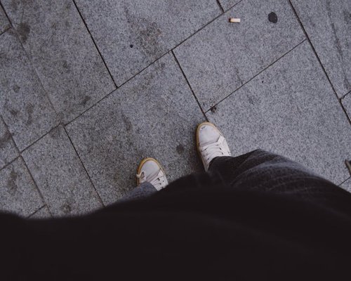 Sneakers walking on a paved city sidewalk