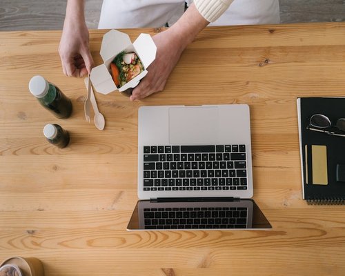 Person eating a healthy bowl at a bright table away from computer