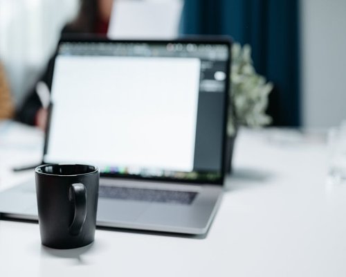 Laptop and coffee cup on a busy office desk